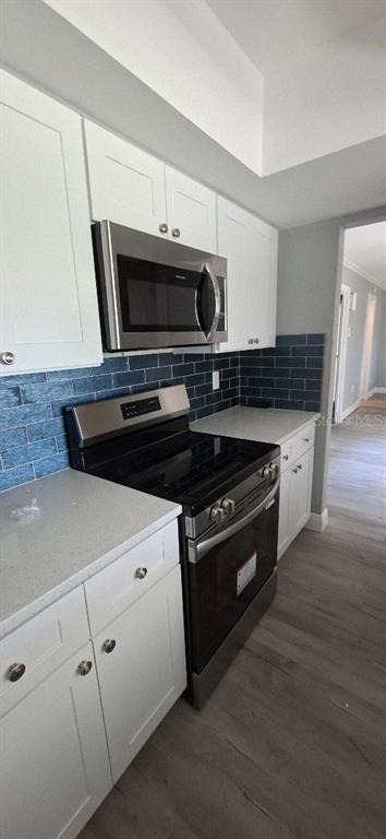 A kitchen features white cabinets, stainless steel appliances, and a blue subway tile backsplash — 4836 ONYX LANE, NEW PORT RICHEY, FL