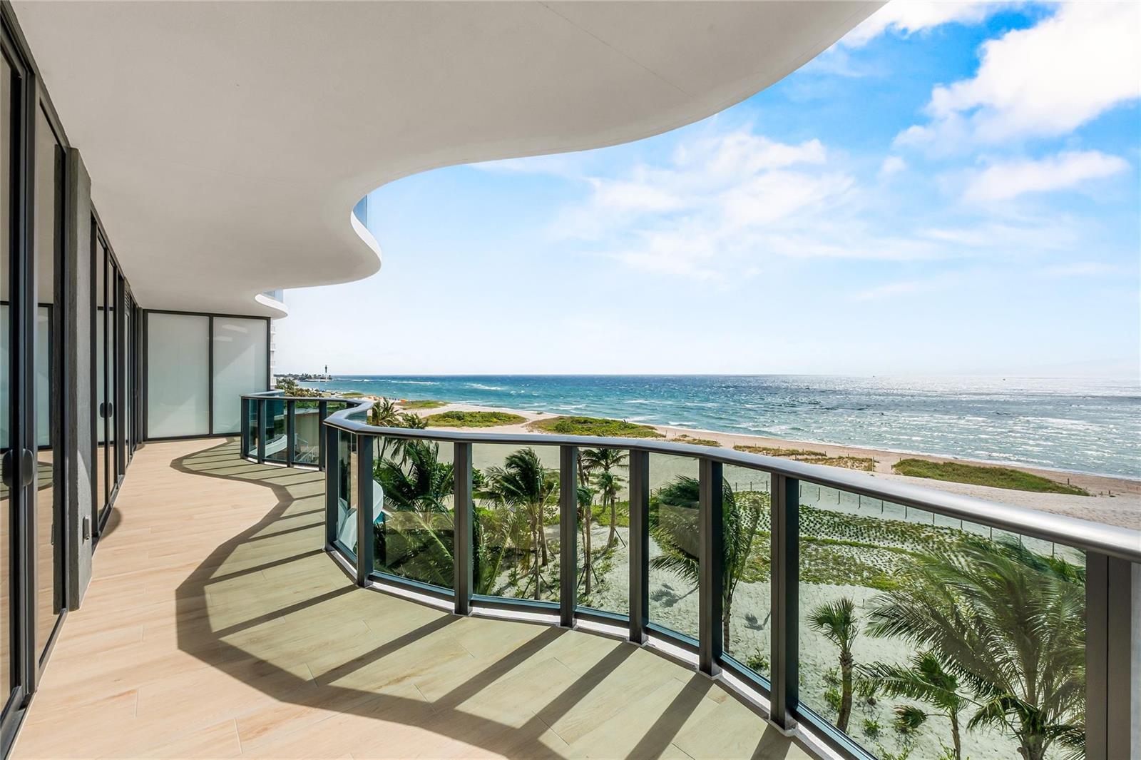 A curved balcony with glass railings overlooks a sandy beach and the ocean — 900 N Ocean Boulevard # 505, Pompano Beach FL 33062, POMPANO BEACH, FL