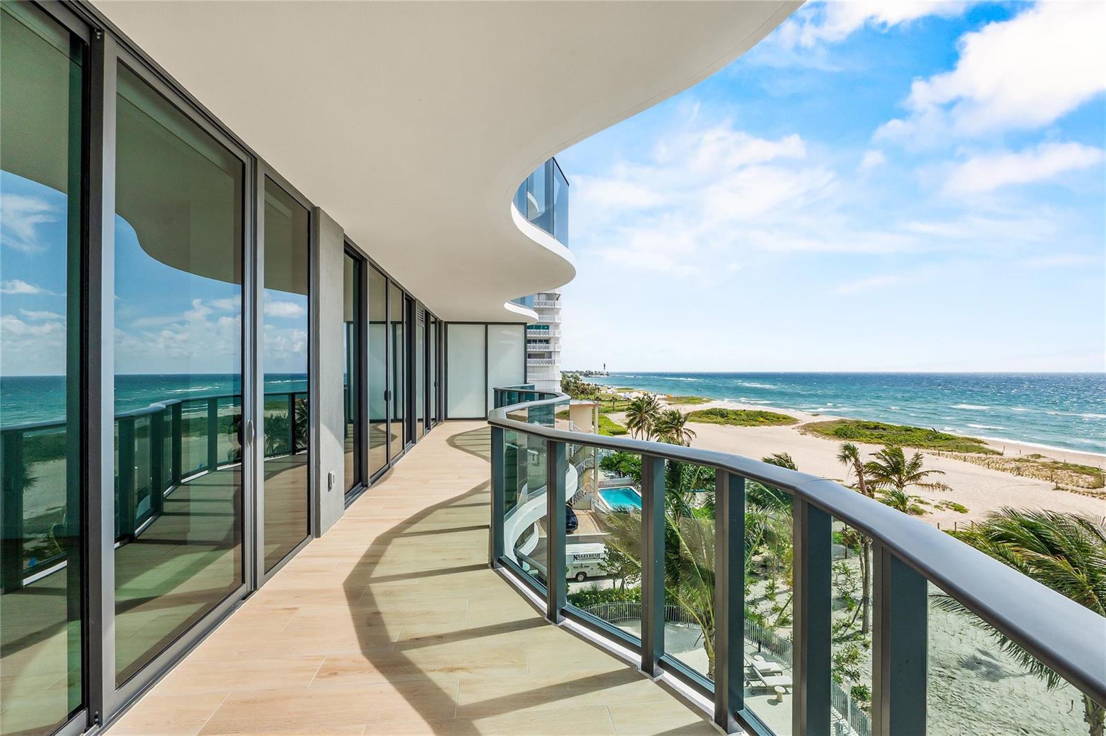 A curved balcony with glass railings overlooks a sandy beach and the ocean — 900 N Ocean Boulevard # 505, Pompano Beach FL 33062, POMPANO BEACH, FL