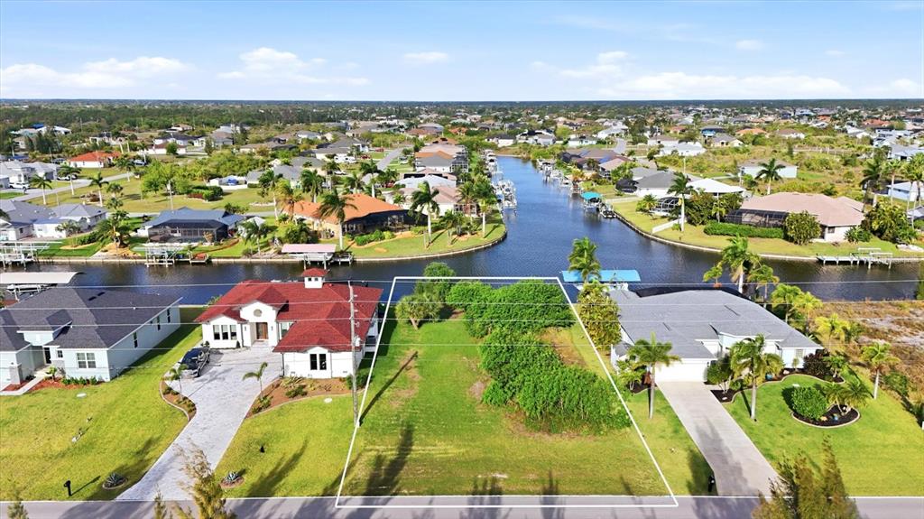 An aerial view shows a vacant residential lot situated between two houses along a canal — 9413 ST PAUL DRIVE, PORT CHARLOTTE, FL