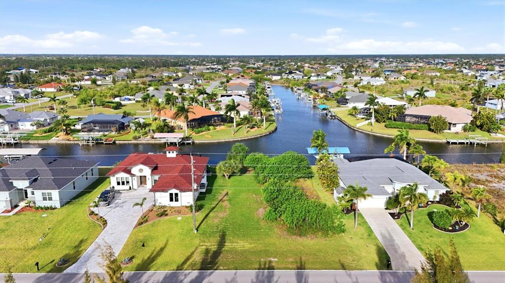 An aerial view shows a vacant lot situated between two houses along a canal — 9413 ST PAUL DRIVE, PORT CHARLOTTE, FL