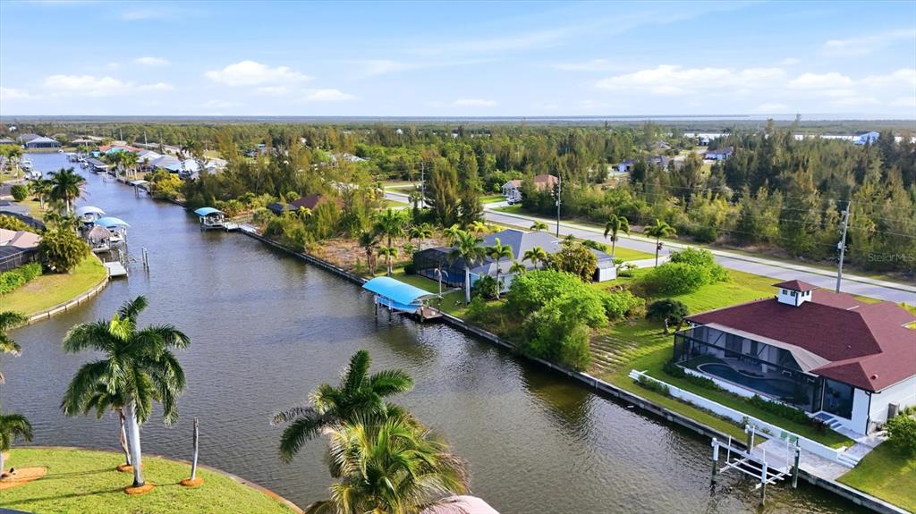 An aerial view shows houses along a canal with boat docks and palm trees — 9413 ST PAUL DRIVE, PORT CHARLOTTE, FL