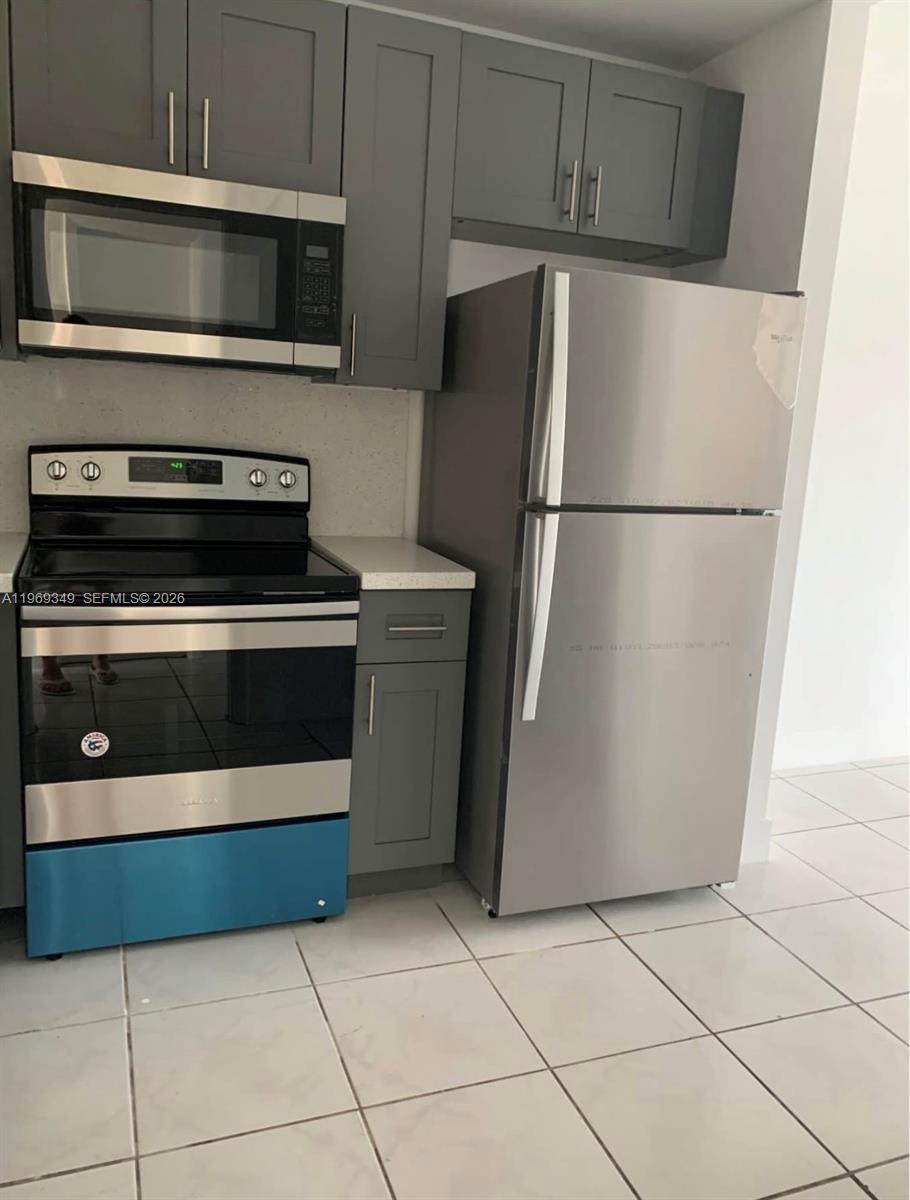 A kitchen features gray cabinets, stainless steel appliances, and white tile flooring — 7505 SW 82nd St # 306, Miami FL 33143, MIAMI, FL