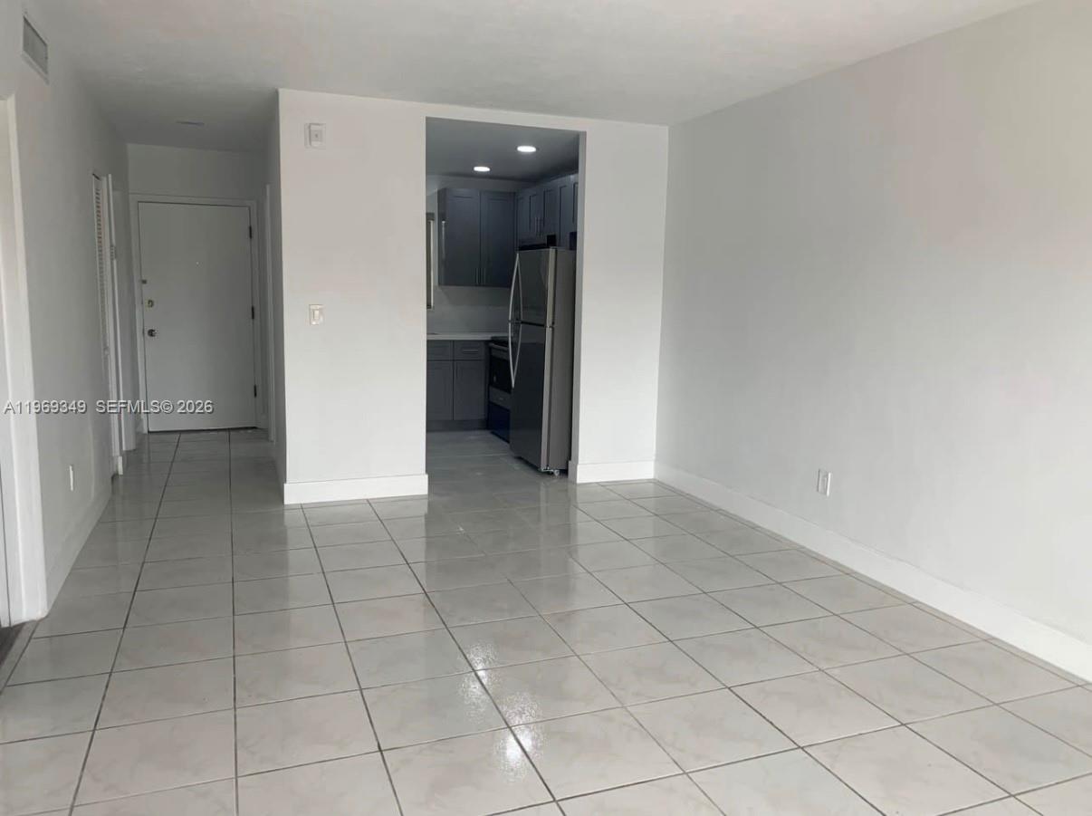 A tiled living area leads into a kitchen with gray cabinets and stainless steel appliances — 7505 SW 82nd St # 306, Miami FL 33143, MIAMI, FL