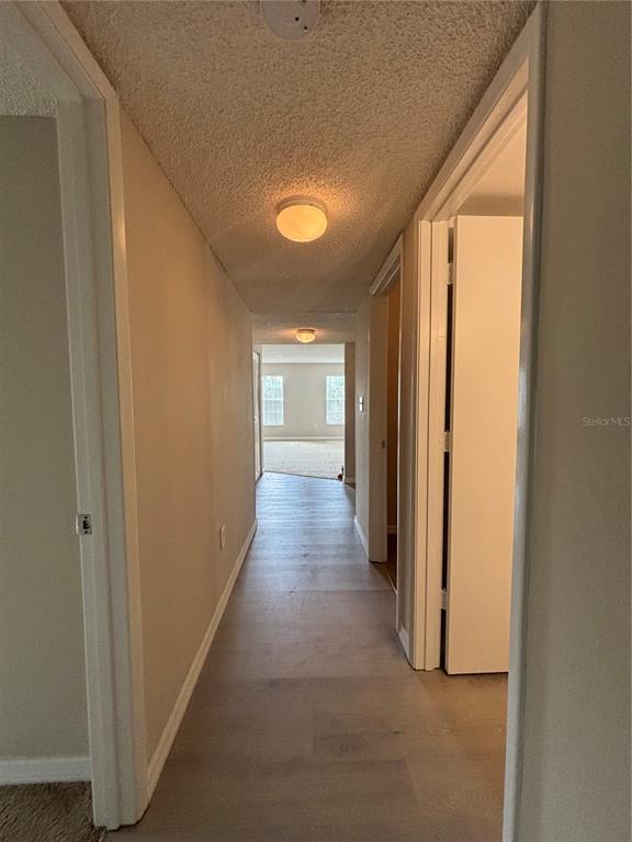 A hallway with light-colored flooring leads toward a room with windows and carpeted floors — 2690 CORAL LANDINGS BOULEVARD UNIT 631, PALM HARBOR, FL