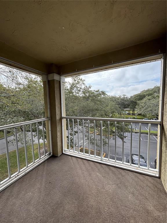 A screened-in balcony with a concrete floor overlooks a parking lot and trees — 2690 CORAL LANDINGS BOULEVARD UNIT 631, PALM HARBOR, FL