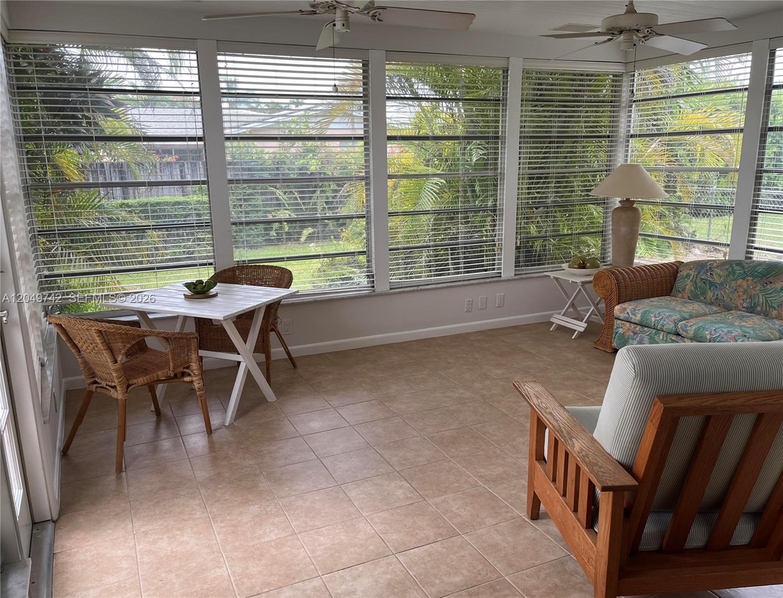 A sunroom features tile flooring, wicker furniture, a small dining table, and large windowed walls — 5831 SW 89th Ct, Miami FL 33173, MIAMI, FL