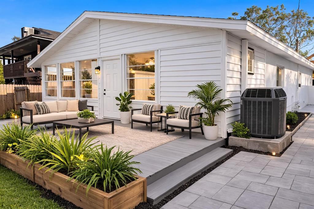 A white house exterior features a grey deck, patio furniture, and a raised wooden planter — 1827 MONTANA AVENUE NE, ST PETERSBURG, FL