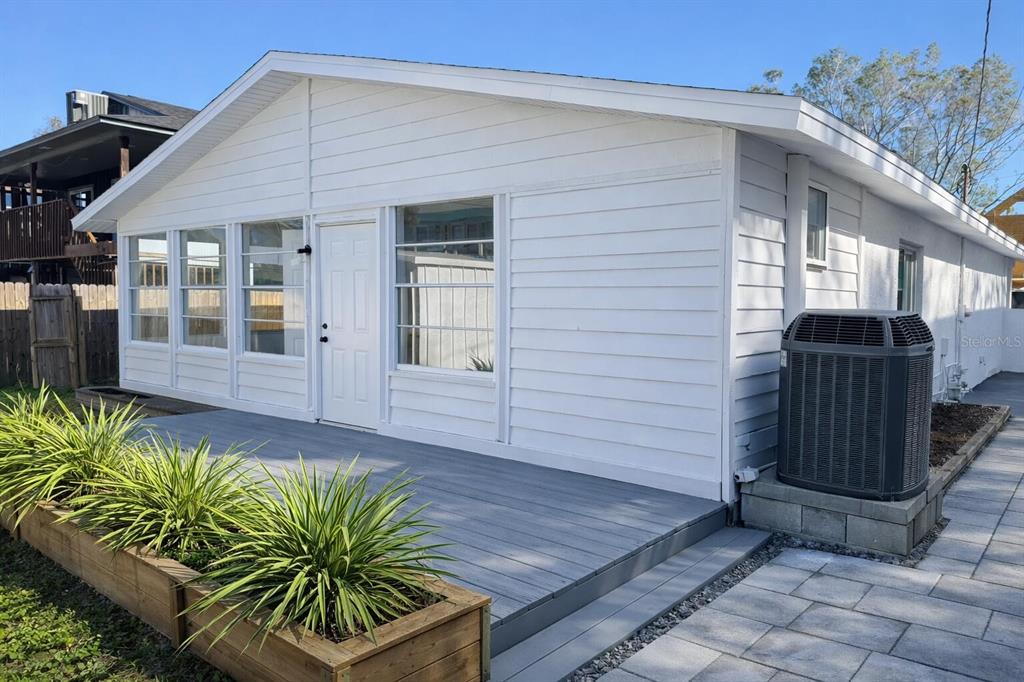A white house exterior features a gray deck, a white door, and a central air unit — 1827 MONTANA AVENUE NE, ST PETERSBURG, FL