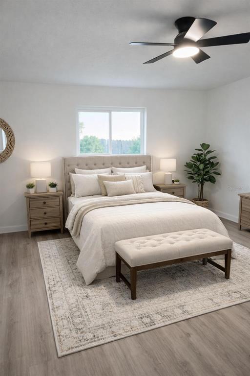 This bedroom features a tufted headboard, light wood flooring, and a ceiling fan — 1827 MONTANA AVENUE NE, ST PETERSBURG, FL