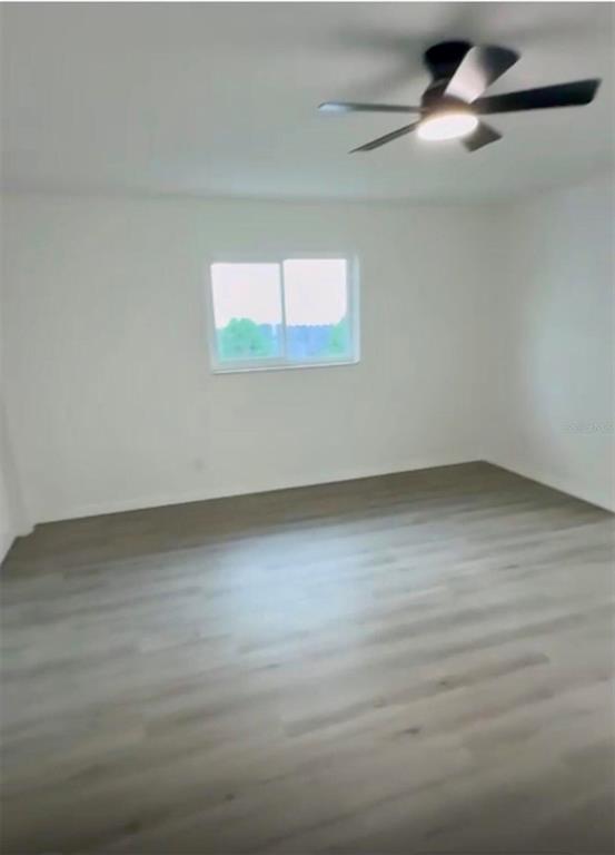 An empty room features light-colored wood-look flooring, white walls, and a ceiling fan — 1827 MONTANA AVENUE NE, ST PETERSBURG, FL