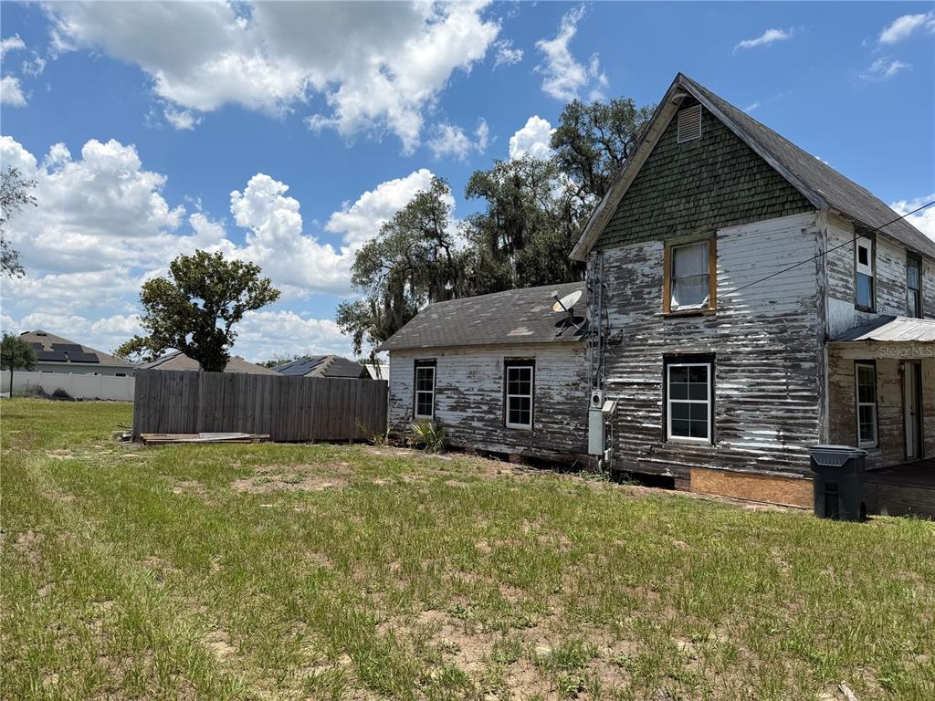 A weathered two-story house with peeling white paint stands in a grassy yard — 6115 COUNTY ROAD N, DAVENPORT, FL