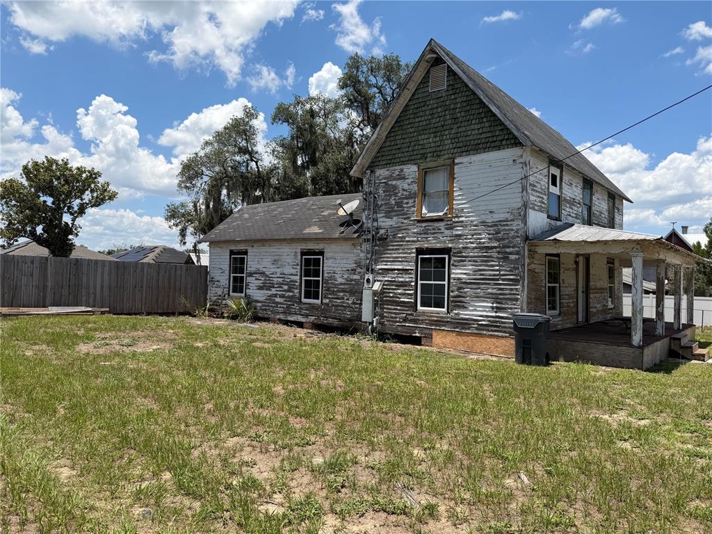 A weathered two-story house with peeling white paint and a front porch sits on grass — 6115 COUNTY ROAD N, DAVENPORT, FL