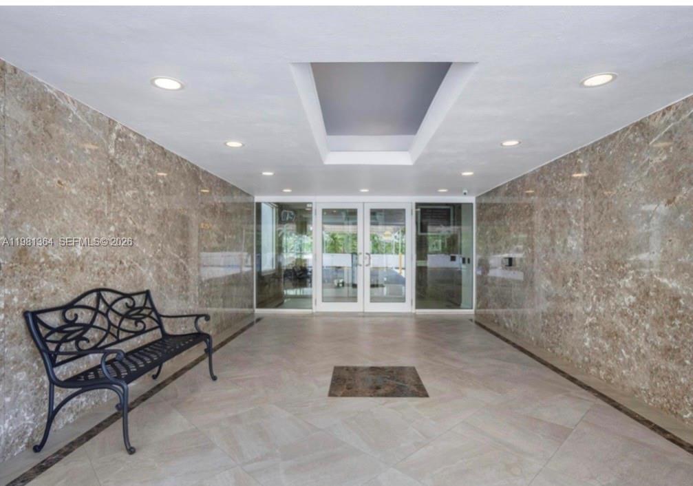 A building lobby features marble walls, a wrought iron bench, and a recessed ceiling light — 1370 S Ocean Blvd # 1506, Pompano Beach FL 33062, POMPANO BEACH, FL