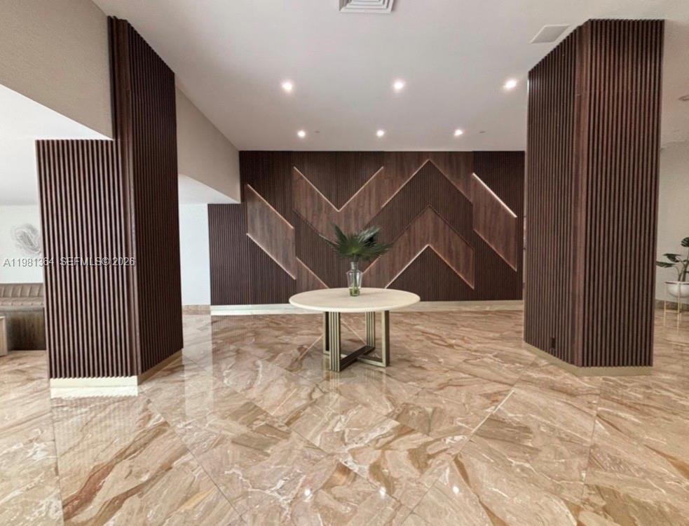 A lobby features a round table, marble flooring, and wood-paneled walls with chevron accents — 1370 S Ocean Blvd # 1506, Pompano Beach FL 33062, POMPANO BEACH, FL