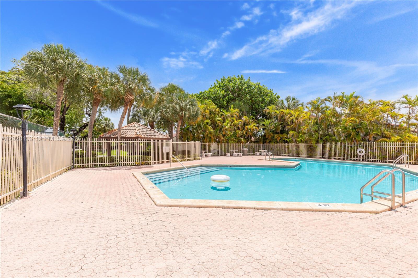 A swimming pool with a white fence and palm trees under a blue sky — 9055 SW 149th Pl, Miami FL 33196, MIAMI, FL