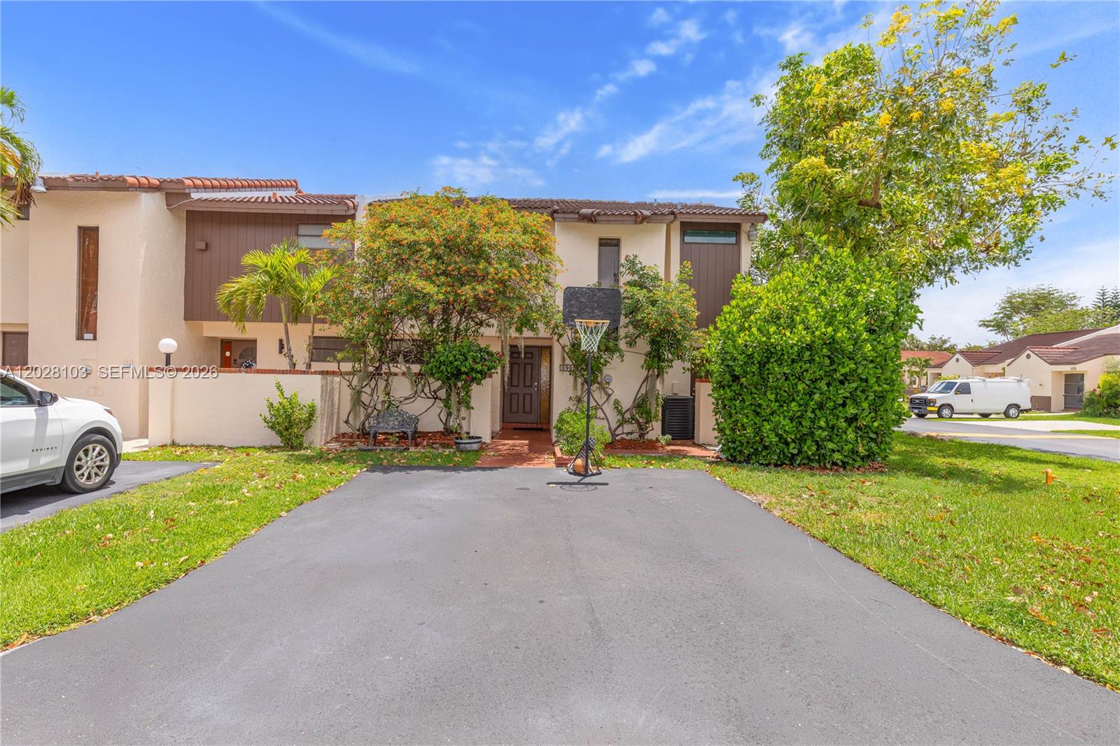 A two-story townhouse features a paved driveway, a basketball hoop, and mature landscaping — 9055 SW 149th Pl, Miami FL 33196, MIAMI, FL