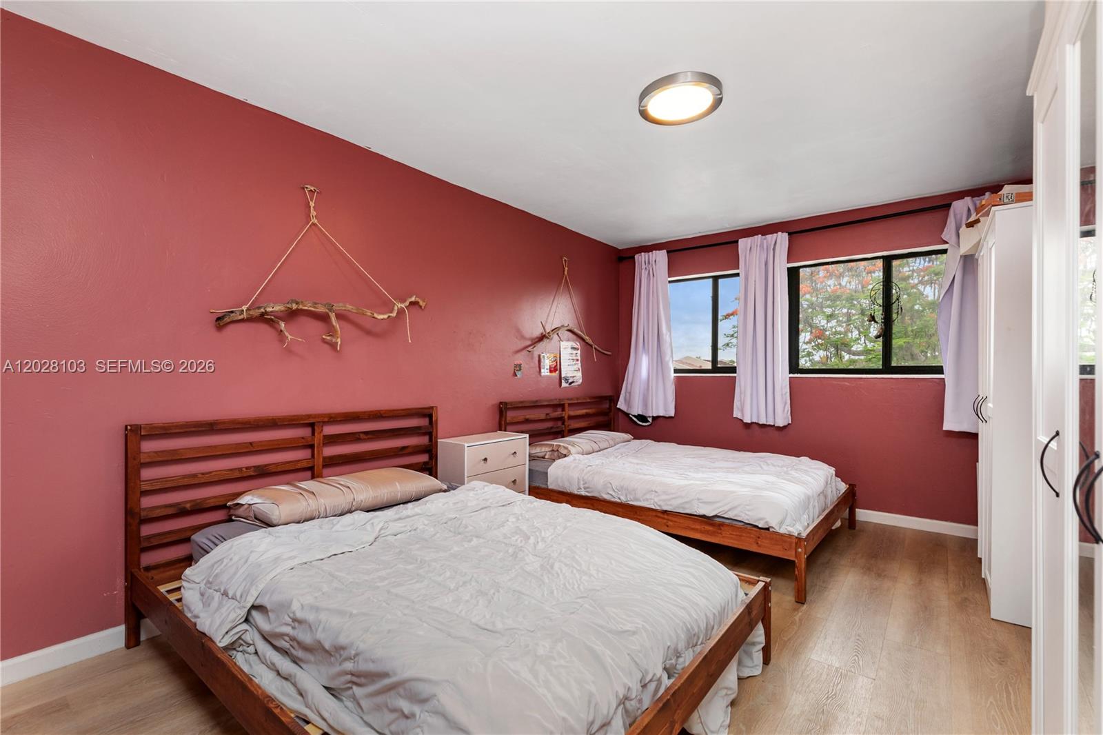 A bedroom features two wooden beds, red walls, light wood flooring, and a white wardrobe — 9055 SW 149th Pl, Miami FL 33196, MIAMI, FL