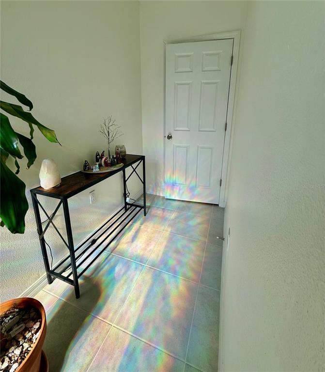 A hallway features a console table, tile flooring, and colorful light refractions on the floor — 1478 SEA GLASS ROAD, HAINES CITY, FL
