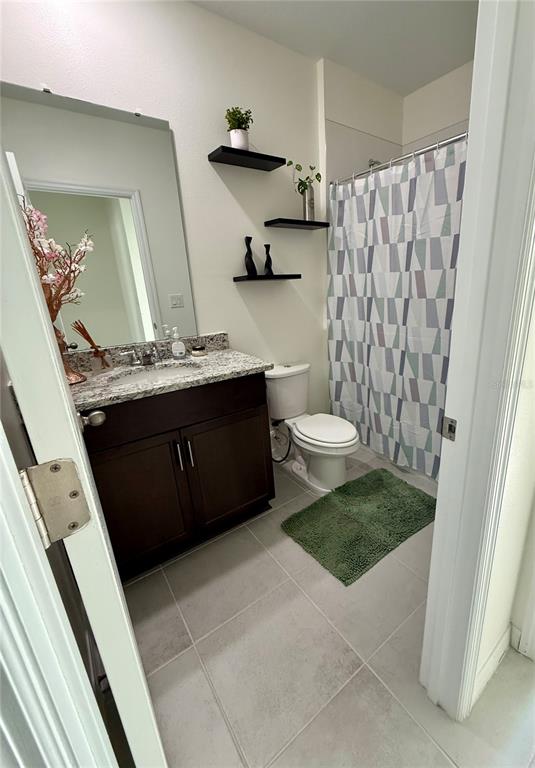 A bathroom features a dark wood vanity, granite countertop, floating shelves, and a patterned shower curtain — 1478 SEA GLASS ROAD, HAINES CITY, FL