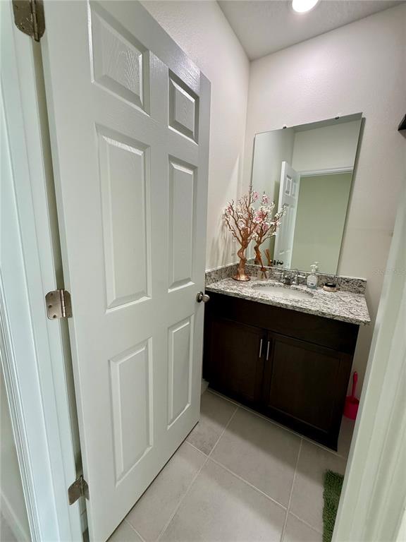 A small bathroom features a dark wood vanity, granite countertop, and a white paneled door — 1478 SEA GLASS ROAD, HAINES CITY, FL
