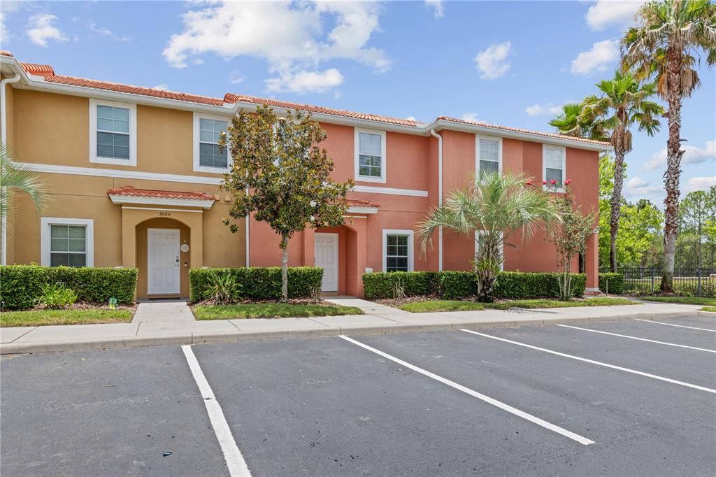 A two-story townhouse exterior with a parking lot in the foreground — 3003 BIRD OF PARADISE LANE, KISSIMMEE, FL