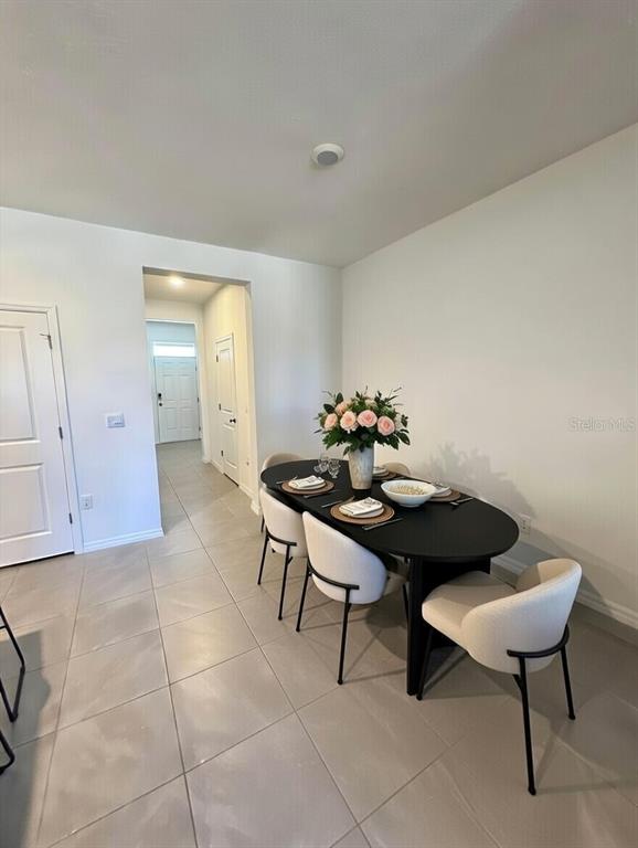 A dining area features a black oval table with four chairs and a floral centerpiece — 32599 TURTLE GRACE LOOP, WESLEY CHAPEL, FL