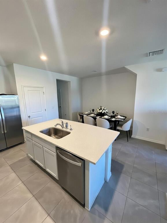 A kitchen island with a stainless steel sink and dishwasher sits before a dining area — 32599 TURTLE GRACE LOOP, WESLEY CHAPEL, FL