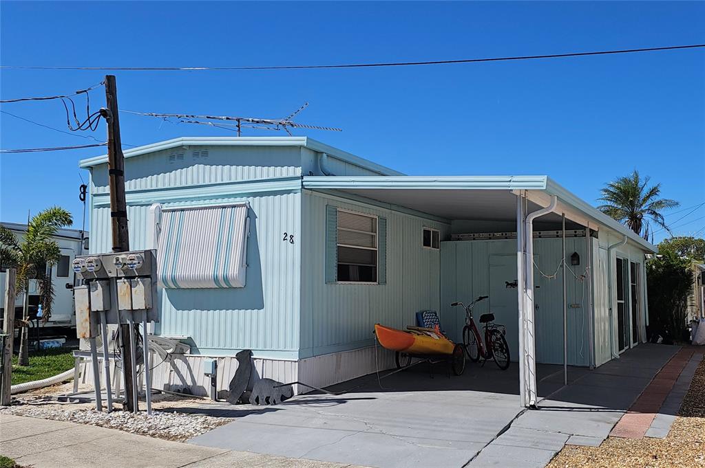 A light blue mobile home with a carport, a kayak, and a bicycle parked outside — 10315 CORTEZ ROAD W UNIT 28-1, BRADENTON, FL