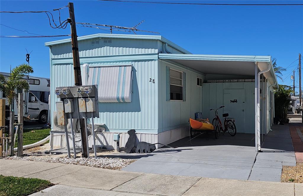 A light blue mobile home features a carport, a bicycle, and a kayak — 10315 CORTEZ ROAD W UNIT 28-1, BRADENTON, FL
