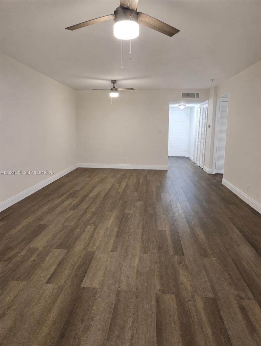 An empty room features light-colored walls, wood-look flooring, and two ceiling fans — LAUDERHILL, FL