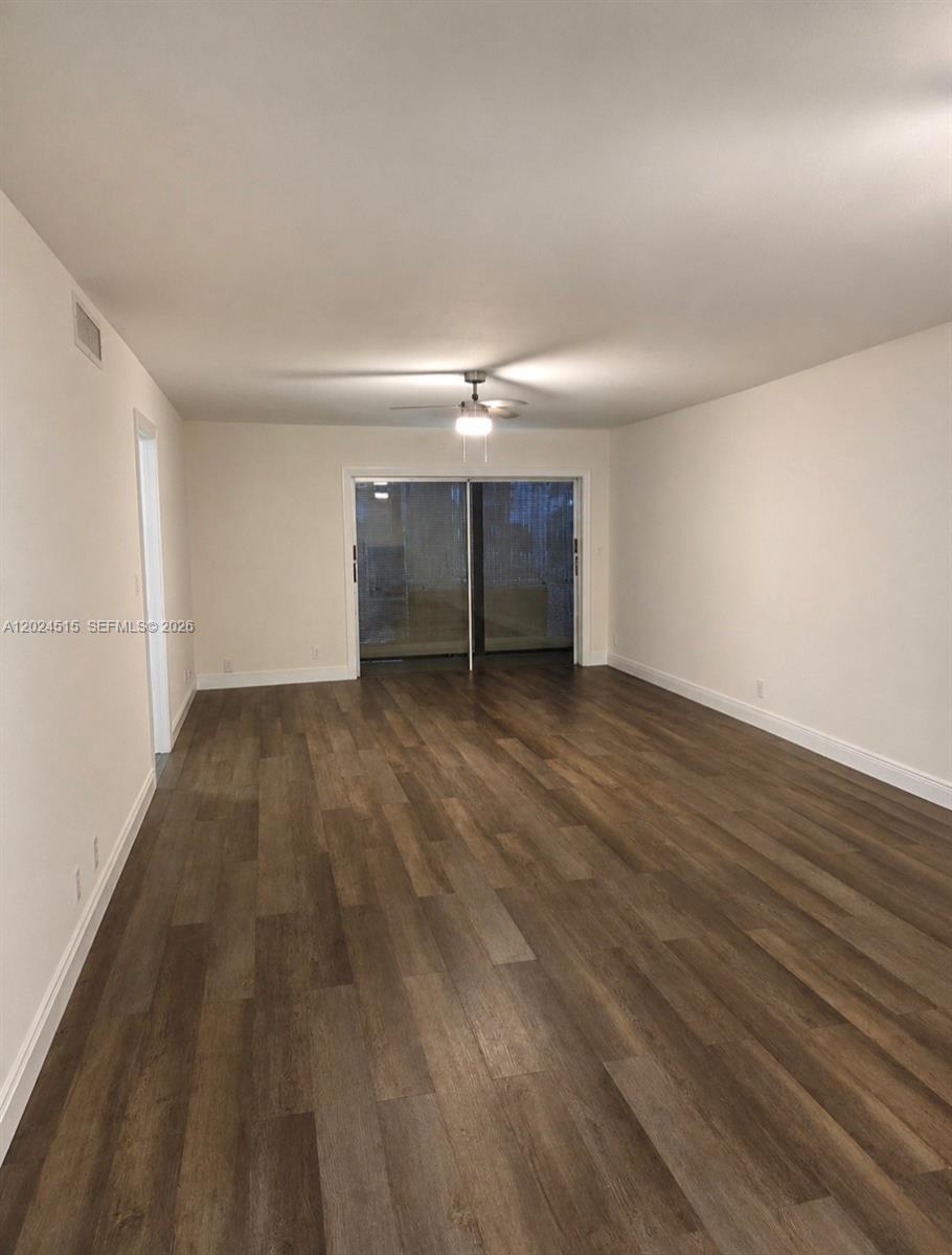 An empty room features white walls, dark wood-look flooring, and a ceiling fan — LAUDERHILL, FL
