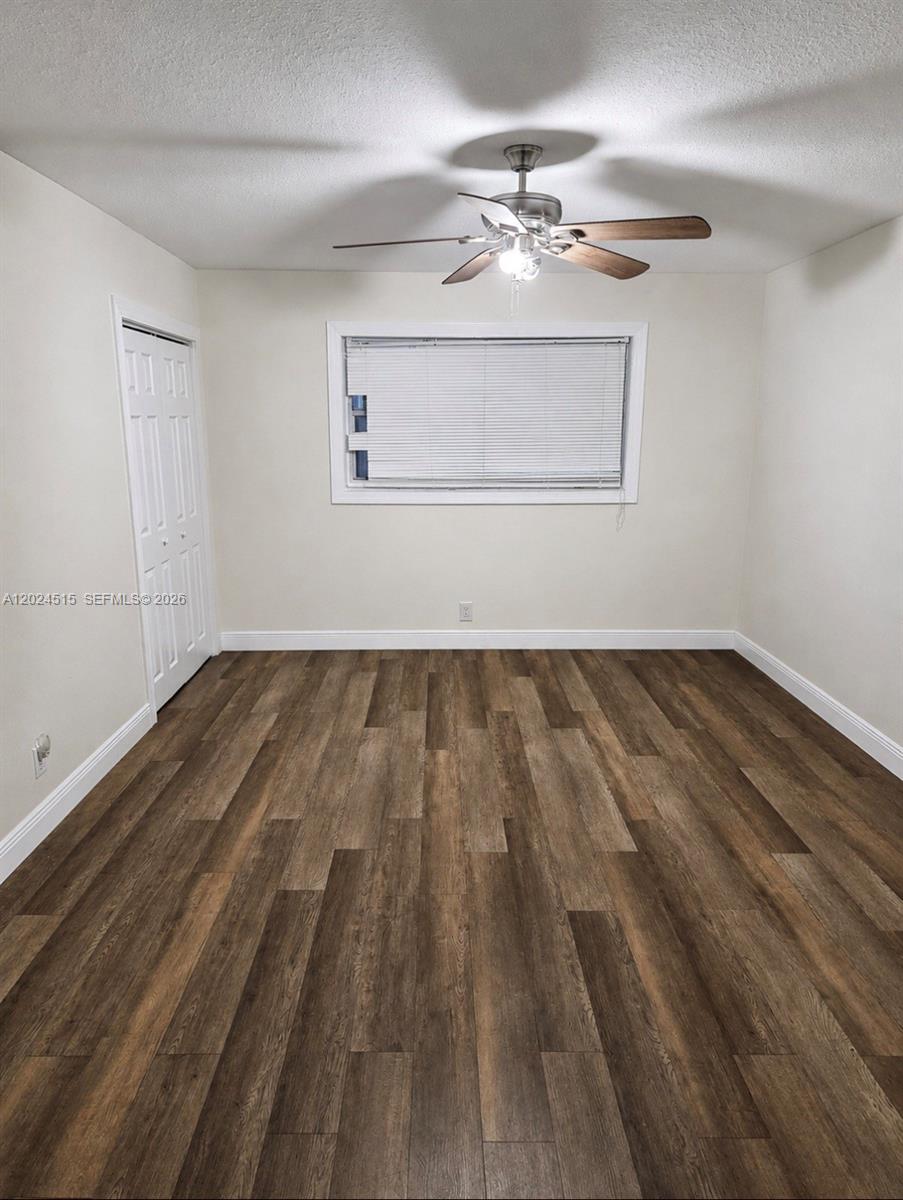 An empty bedroom features wood-look flooring, a ceiling fan, and a window with blinds — LAUDERHILL, FL