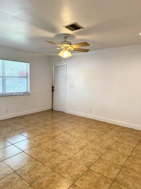 An empty room features tan tile flooring, white walls, a ceiling fan, and a window — 356 SW 2nd Pl # 3, Pompano Beach FL 33060, POMPANO BEACH, FL