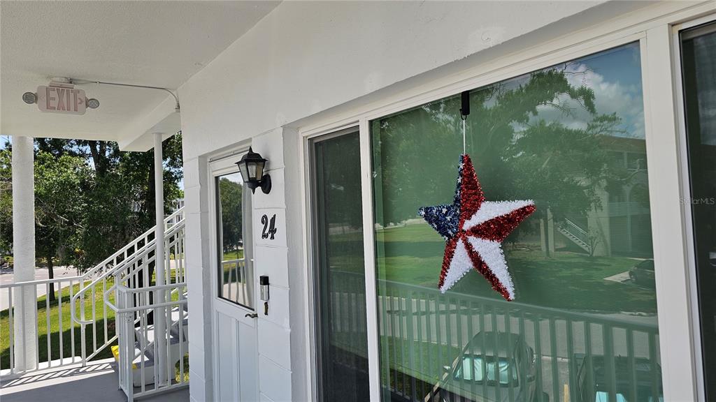 A white exterior wall features a door labeled 24, a window with a star decoration, and stairs — 2430 BRAZILIA DRIVE UNIT 24, CLEARWATER, FL