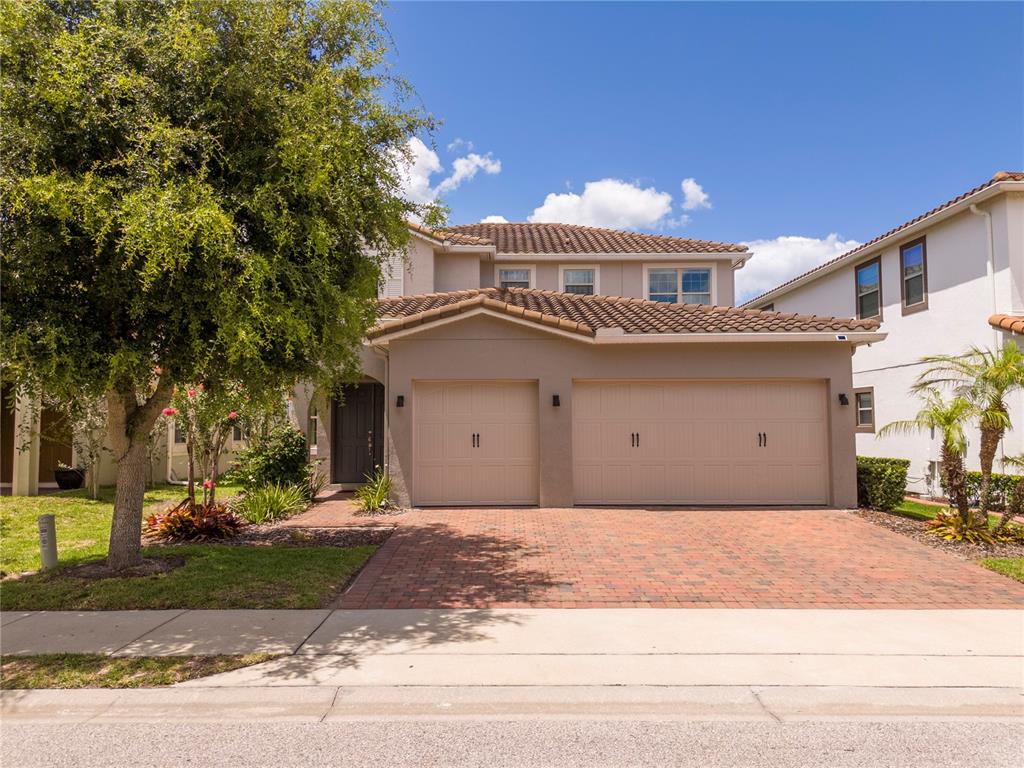 A two-story house with a two-car garage and a brick driveway under a blue sky — 10431 SIDDINGTON DRIVE, ORLANDO, FL