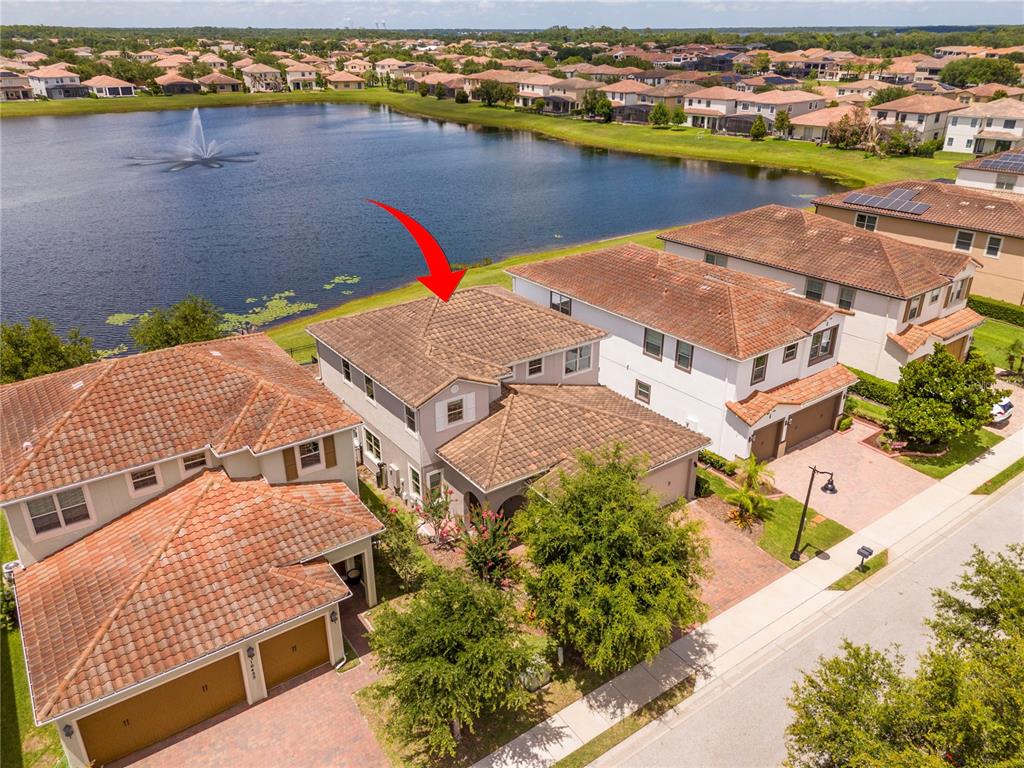 An aerial view shows a two-story house with a tiled roof next to a lake — 10431 SIDDINGTON DRIVE, ORLANDO, FL