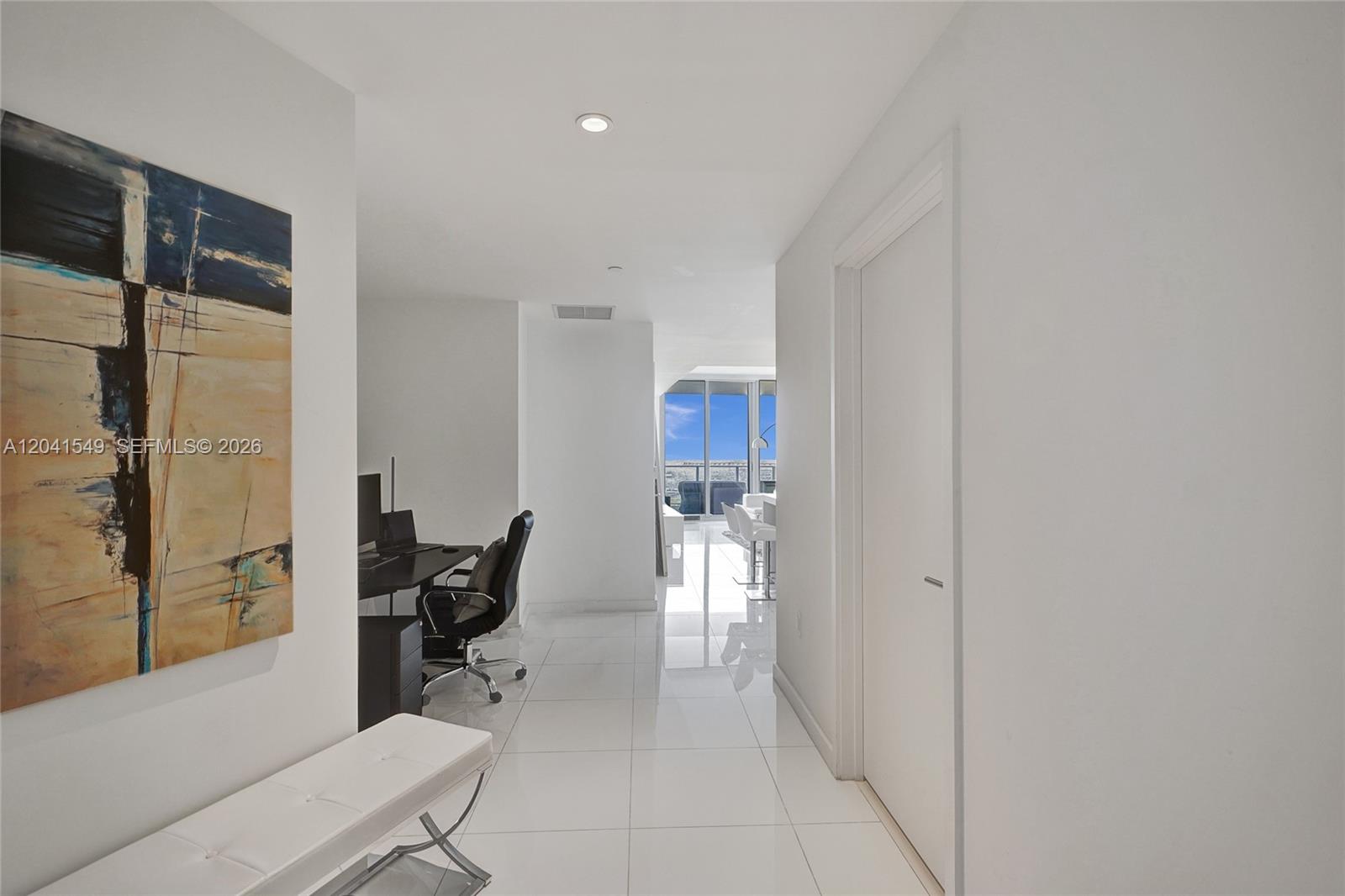 A hallway with white tile floors leads to an office area and a bright living space — 851 NE 1st Ave # 3800, Miami FL 33132, MIAMI, FL