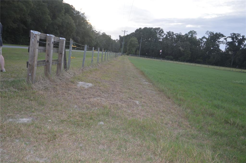 A wooden fence lines a dirt path bordering a grassy field under a cloudy sky — 5640 SW COUNTY ROAD 344, TRENTON, FL