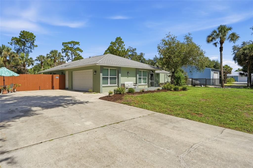 A light green single-story house with a concrete driveway and a wooden fence — 505 THOMPSON AVENUE, LEHIGH ACRES, FL