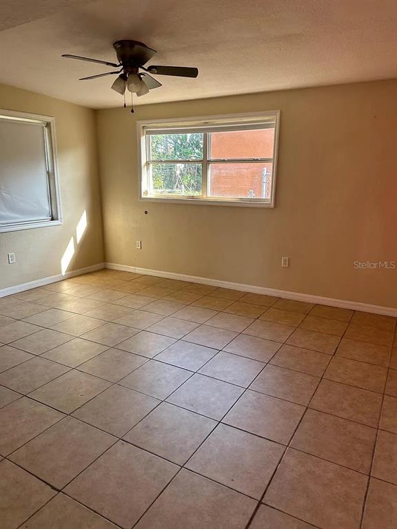 An empty room features beige tile flooring, a ceiling fan, and a single window — 108 EDGEWATER DRIVE, WINTER HAVEN, FL