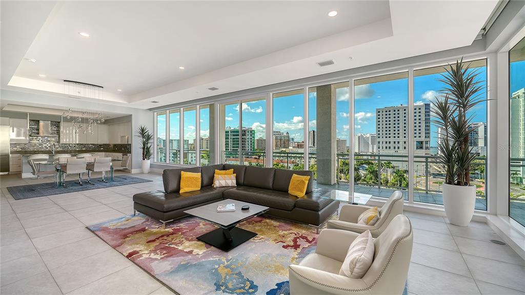 A modern living room and dining area feature floor-to-ceiling windows overlooking a city skyline — 540 N TAMIAMI TRAIL UNIT 804, SARASOTA, FL