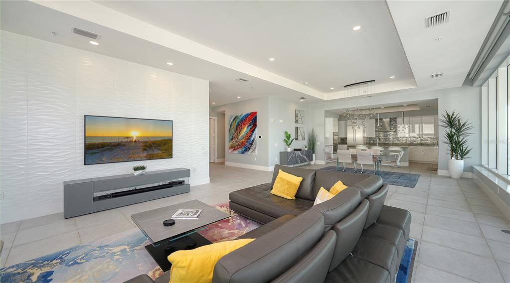 A modern living room features a textured white wall, grey sectional sofa, and open kitchen — 540 N TAMIAMI TRAIL UNIT 804, SARASOTA, FL
