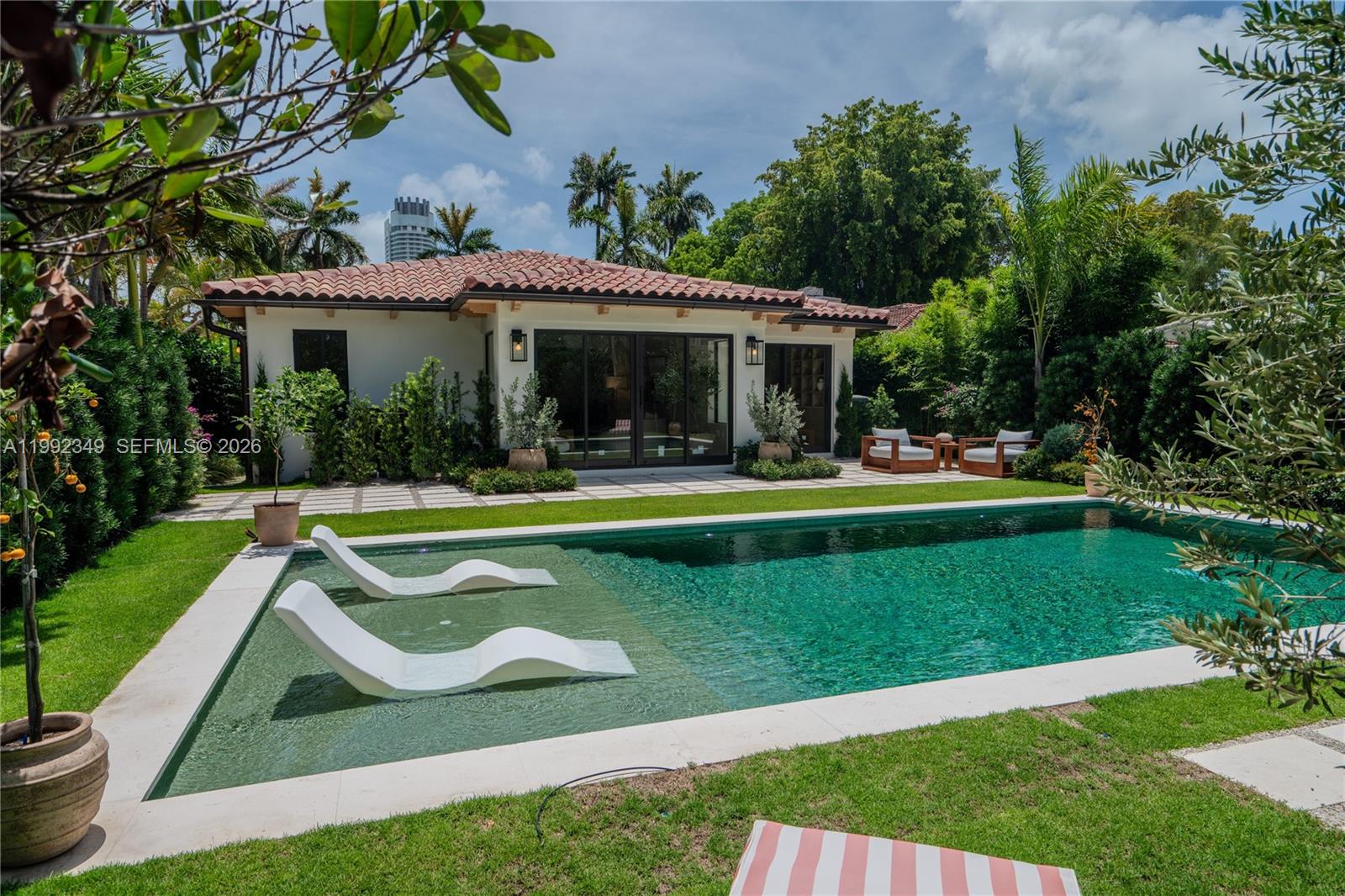 A living room with a curved sofa, round coffee table, and an adjacent dining area — 4430 Royal Palm Ave, Miami Beach FL 33140, MIAMI BEACH, FL