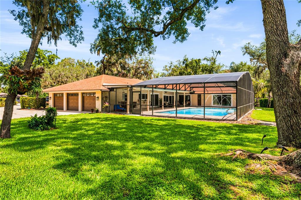 A house with a three-car garage and a screened-in pool sits on a grassy lawn — 111 LITTLE OAK LANE, ALTAMONTE SPRINGS, FL
