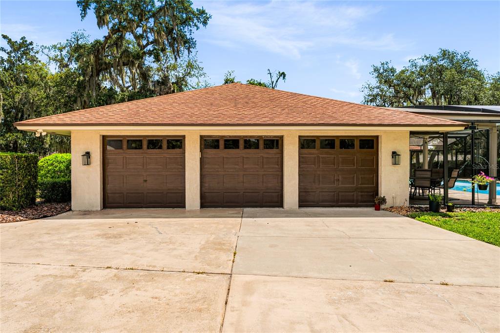 A detached three-car garage with brown doors and a hip roof sits on a driveway — 111 LITTLE OAK LANE, ALTAMONTE SPRINGS, FL