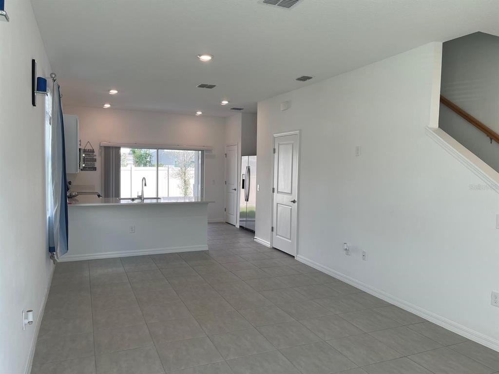 An open-concept living area with tile flooring, a kitchen island, and a staircase — 3335 COMPOSITION STREET, POINCIANA, FL