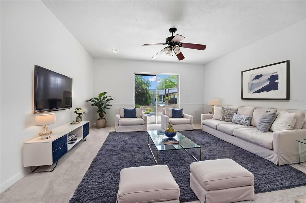 A living room features a large blue rug, white sofa, armchairs, and a glass coffee table — 5060 ANDREA BOULEVARD, ORLANDO, FL