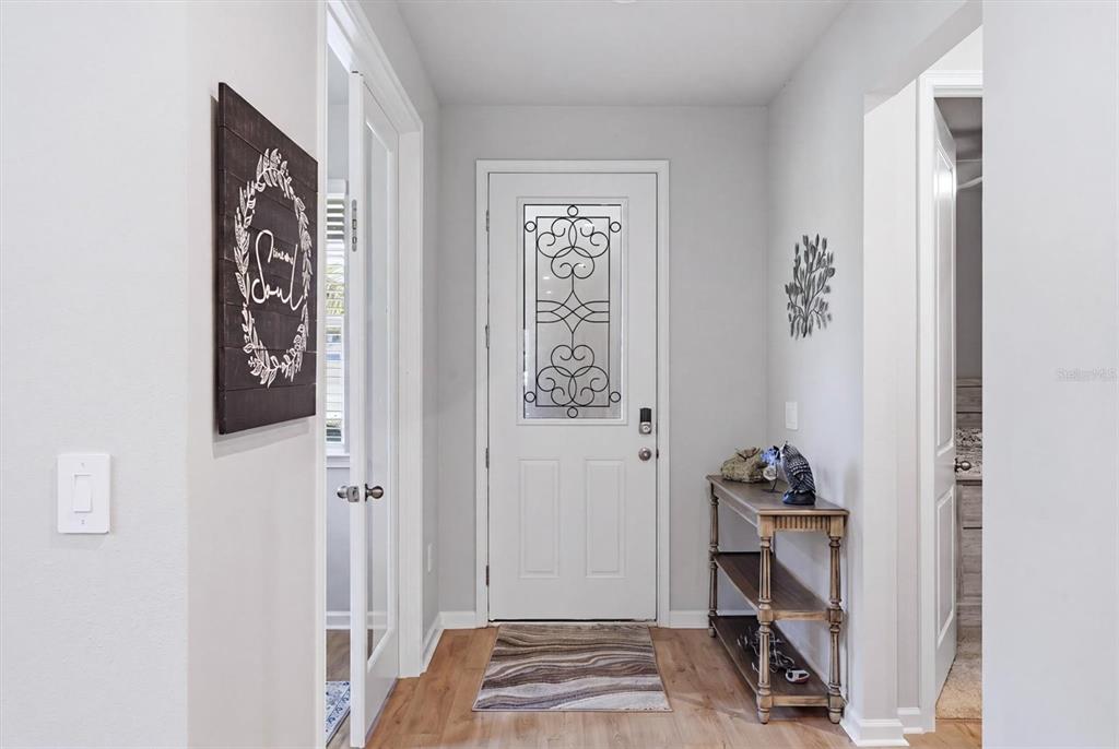 An entryway features a white front door with decorative glass, wood-look flooring, and a console table — 20411 SYMPHONY PLACE, VENICE, FL