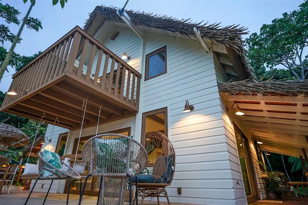A two-story house with white horizontal siding, a thatched roof, and a wooden balcony — CALLE 9 Mameyes II COLINAS DEL YUNQUE UNIT 19 I, RIO GRANDE, PR